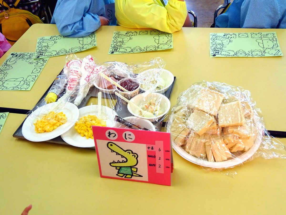 お別れ会のごちそう。子どもたちが描いたランチョンマットの上にサンドイッチの具材が並ぶ
