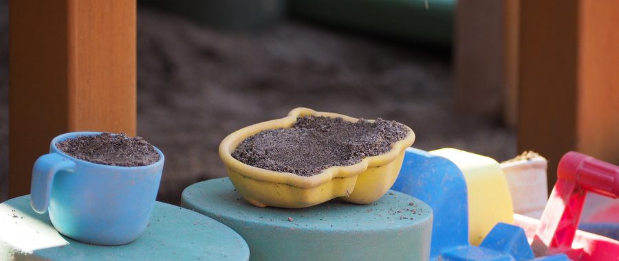 砂場のおままごと。水色のカップと黄色い器に砂が盛られている